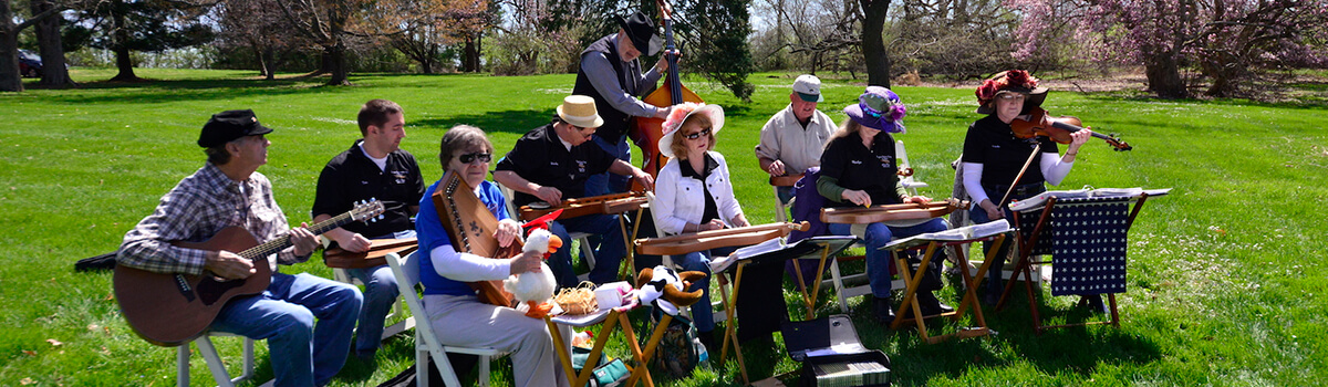 Corydon Dulcimer Society members gathered together outside on a sunny day playing their instruments