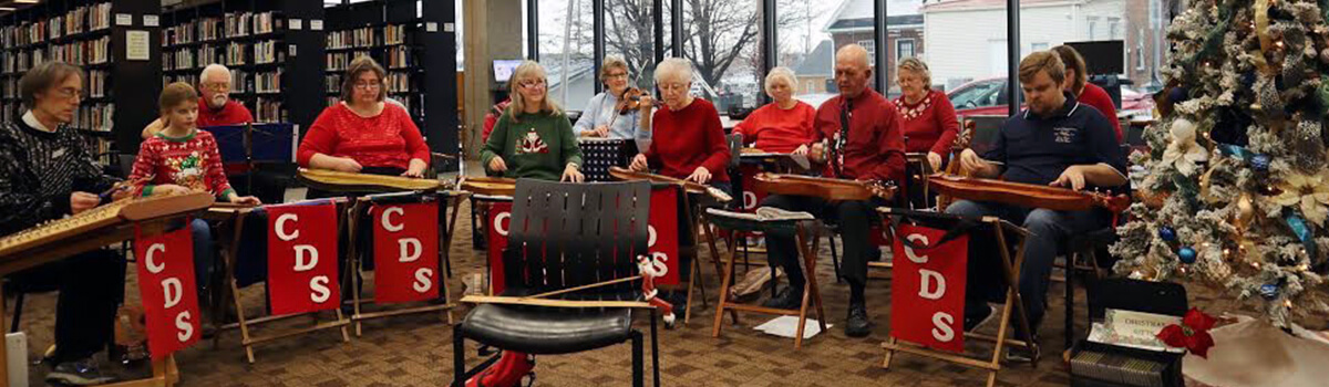 Corydon Dulcimer Society members gathered together outside on a sunny day playing their instruments